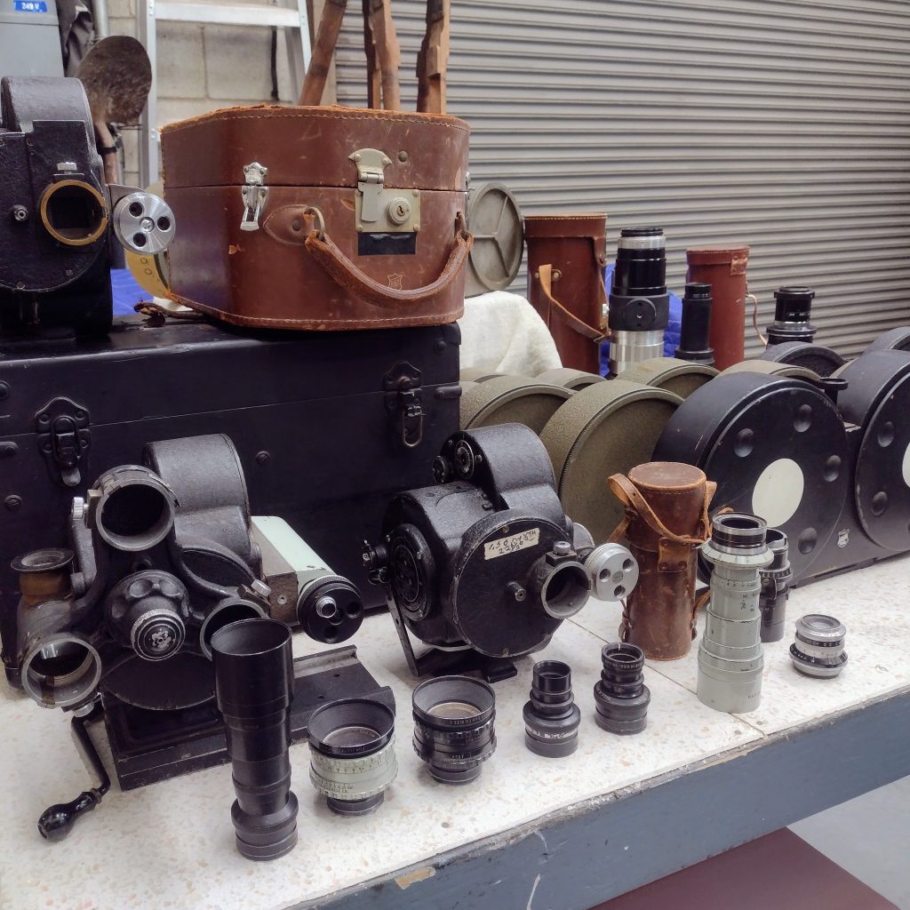 A close-up of Bell & Howell Eyemo cameras, camera cases, and lenses.