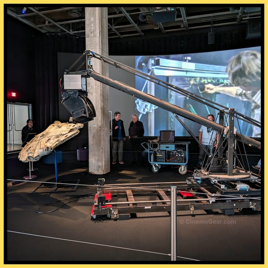 A view of the Dykstraflex and the model of the Millennium Falcon built by model maker Sean Sides. In the background you can see Gene Kozicki and Richard Edlund standing near the column and a video about the history and development of the Dykstraflex is playing on the screen.